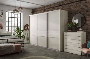 Modern industrial bedroom example with brick walls and white wardrobes.