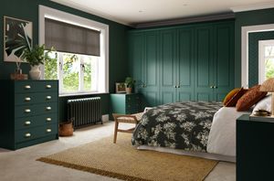 Modern bedroom featuring dark green cupboards with gold fixtures.